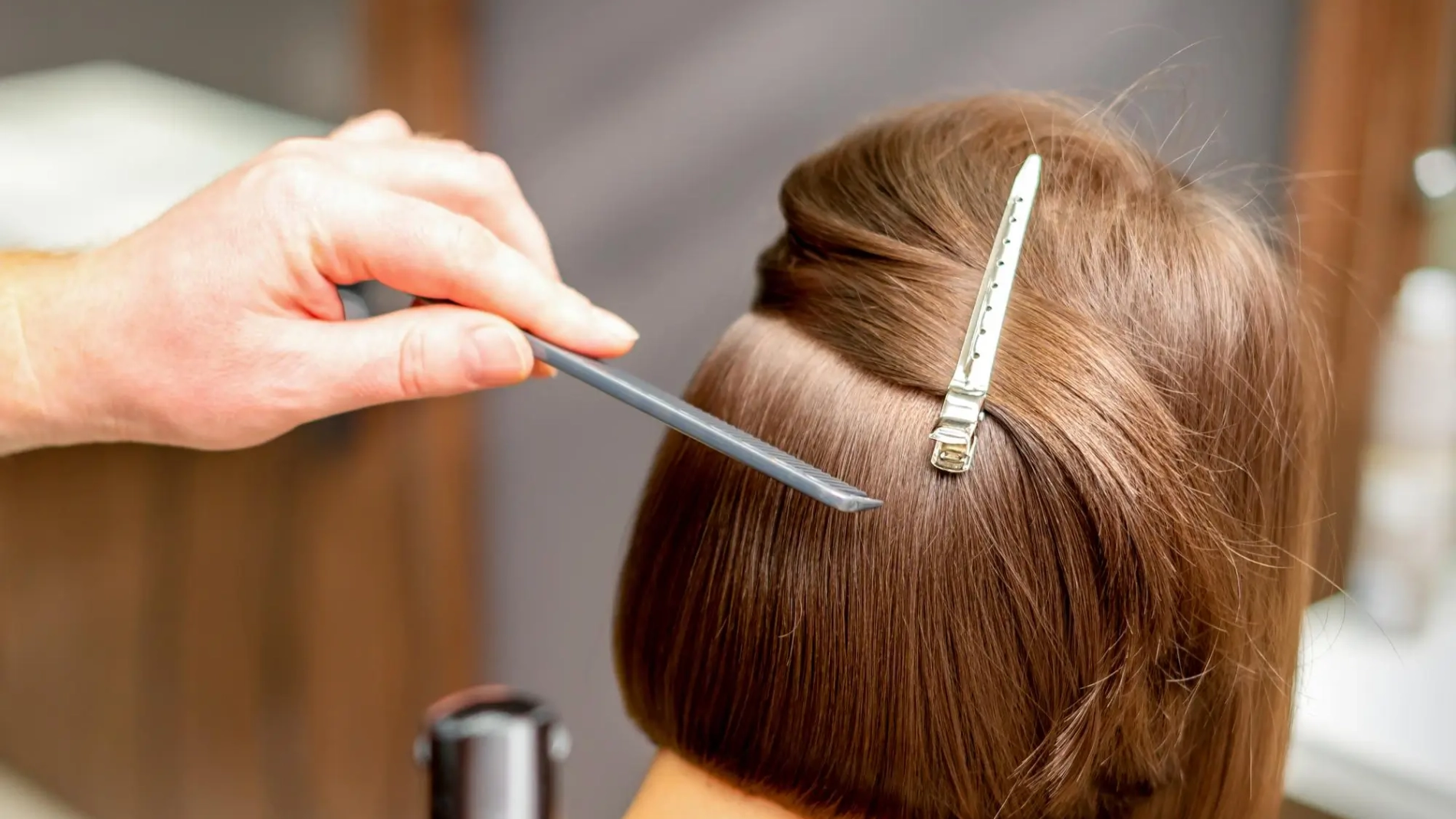 hairstylist-is-straightening-short-hair-young-brunette-woman-with-flat-iron-hairdresser-salon-close-up_141172-10045